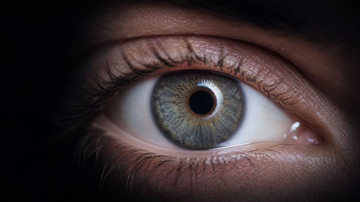 Close-up of an eye lit by the soft ring glow of a surgical microscope