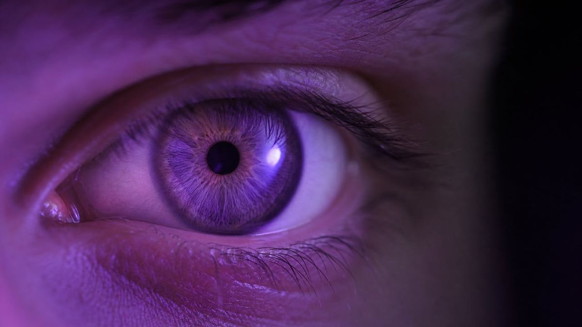 Close-up of an eye under violet light, the color used to adjust the Light Adjustable Lens
