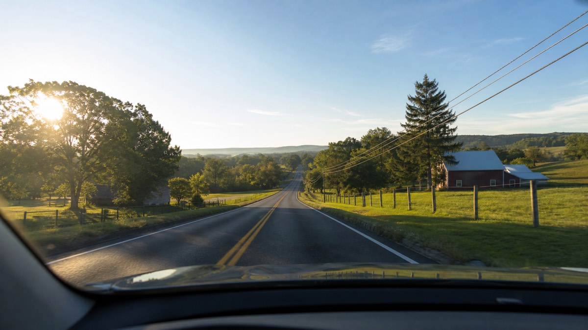 View through a car windshield of a two-lane country road at sunrise, illustrating the familiar-route analogy for a second cataract surgery