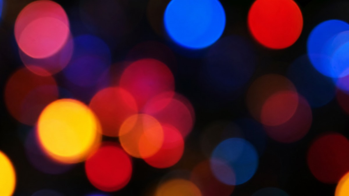 Soft out-of-focus circles of blue, red, pink and yellow light on a dark background, illustrating the shifting colors patients describe seeing during cataract surgery